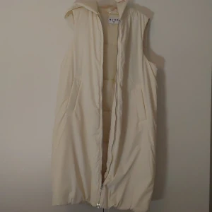 Väst - Säljer denna crèmefärgade västen. Använt  endast 2 ggr då den är för stor. Vadderad. Midilängd. 