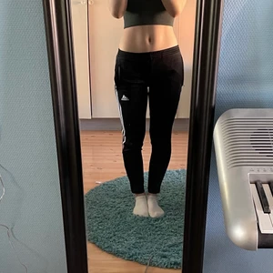 Adidas byxor - Träningsbyxor från Adidas med ränder på sidan. 🏋️‍♀️ Knappt synbara stänk av vit färg finns på framsidan. Dragkedjefickor finns på varje sida👍 Storleken gäller för barnstorlekar, dvs rekommenderas för personer som är runt 152cm långa🤩