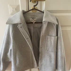 NA-KD jacka - Jättefin grå jacka från NA-KD. Storlek 34 men passar även större storlekar beroende på önskad passform🥰🥰 några fläckar på rygg (syns i bild 2), har ej försökt få bort dom, men om man tvättar den borde dom gå bort👌🏼