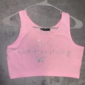 En rosa topp med paljetter med texten ”girls can do anything” 