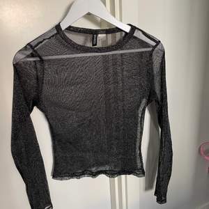En svart-glittrig mesh tröja från H&M, i fint skick och använd fåtal gånger. Priset är inkl frakt