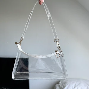 Handväska - Genomskinlig handväska som jag köpt av en tjej här på Plick! Tror den är från Shein o den är i begagnat men fint skick ❤️‍🔥 Går att bära över axeln! Den har blivit lite repig, men det är inget som förstör helheten enligt mig ☺️ Fraktas spårbart för 49 kr 💌