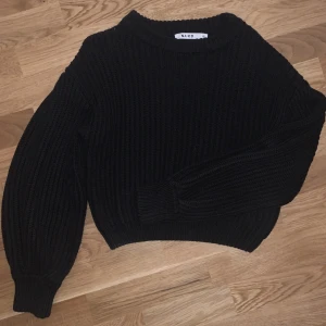 Stickad tröja - En svart stickad tröja med ballongärmar ifrån NA-KD. Tröjan har något tjockare kanter/mudd vid nacke och händer. Ribbat material. Nyskick, aldrig använd.