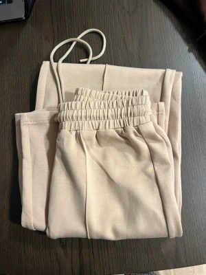 Byxor - Byxor i mjuk tyg i beige färg. Oanvända 