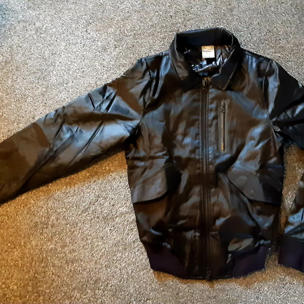 Nike jacka i satinmaterial, se bilder för mått. Verkar knappt använd. Märkt storlek S. Många detaljer, fickor med knappar samt rejäla muddar.. Takit.