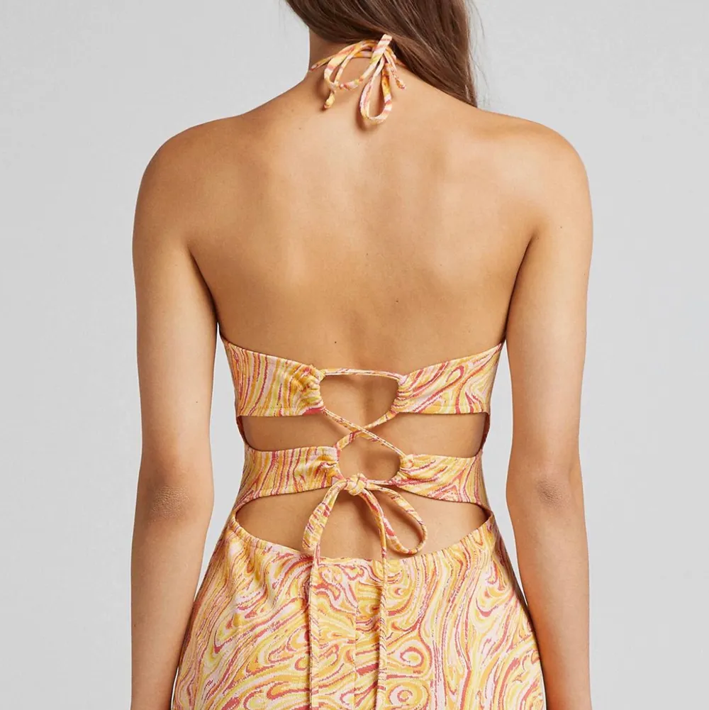 En skitsnygg klänning från Bershka med gult/orange/rött/rosa mönster!!! Halterneck med knyt i ryggen, strl S, aldrig använd med lappar kvar 🧡. Klänningar.