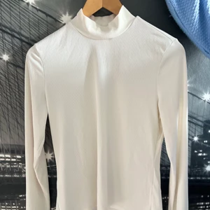 Ribbad polotröja - Vit ribbad polotröja i tunt material som passar bra nu på våren. Sparsamt använd. Storlek M passar även S. Fler bilder finns.