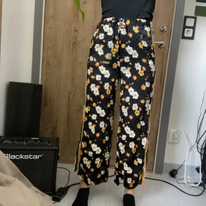 Blommiga byxor  - Supersköna byxor i lite glansigt tyg! Har ett litet snöre i midjan samt två fickor framtill. Från Urban oufitters, i bra skick! 