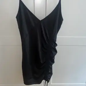 Svart, kort klänning med snörning på sidan från NAKD. Aldrig använd. Pm för fler bilder🖤