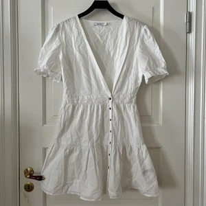 🤍Jättesöt vit klänning från NAKD🤍 - Jättesöt vit klänning från NAKD i storlek 40. Omlott, puffärmar och ”volangig” kjol. Knäpps med knappar. Köpte den på NAKD outlet och en knapp för att knäppa ”omlotten” saknades (se tredje bild), för den ska knäppas på insidan. Har använt en säkerhetsnål.