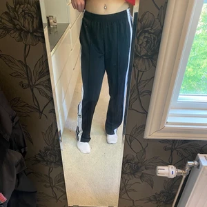 Adidas byxor - Svarta adidasbyxor med knappar på sidorna längst ned. Byxorna är i väldigt skick i storlek M.