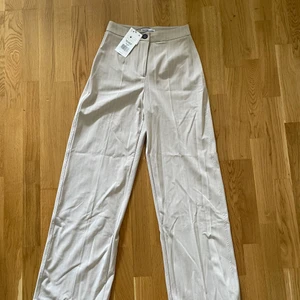 Byxor Bershka - Beiga byxor med vita ränder. Aldrig använda, prislapp kvar. Säljer pga förstora för mig.