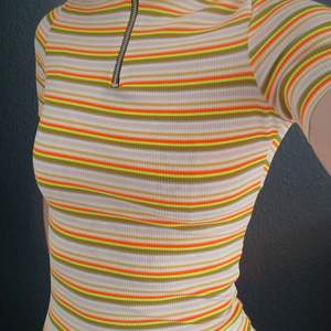 Nyskick. Randig stretchig kort klänning med polokrage och dragkedja. De gula ränderna är neongula.