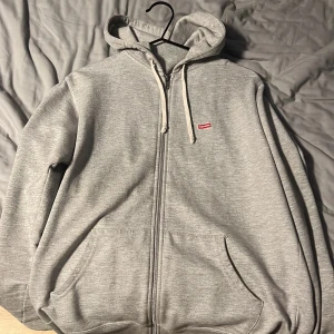 Supreme box logo zip hoodie - En grå supreme bloxlogo zip hoodie i storlek  medium, sitter lite tajt på mig som är 187
