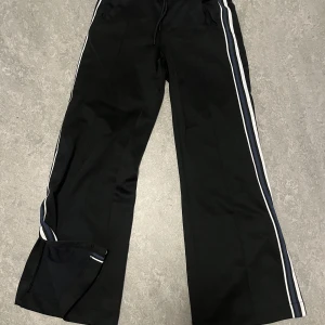 Björn Borg Trackpants - Björnborg vida Trackpants med öppen flare. Blå ränder på sidan samt brodyr på högra baksidan. Inga defekter eller skador. Ingen syn på använda.
