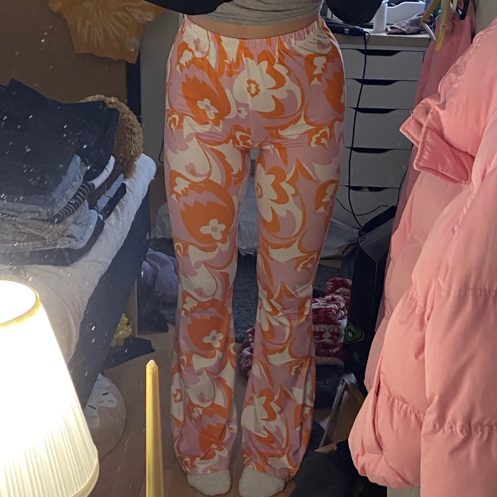 Rosa, orange o vit mönstrade utsvängdabyxor, super sköna och härliga. Sitter skönt och bekvämt. Bootcut, och resår i midjan. Storlek M, från Shein (varan säljs inte längre men bild 2&3 är från deras hemsida).. Jeans & Byxor.