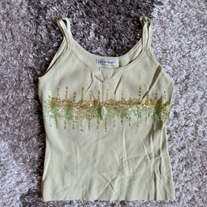 Linne med paljetter  - Ribbat linne, lägger sig så snyggt mot kroppen. Gult med gula paljetter.