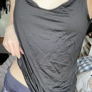 Svart basic topp - En svart topp i ett glansingt tunnt luftigt material! Man kan justera banden👍 