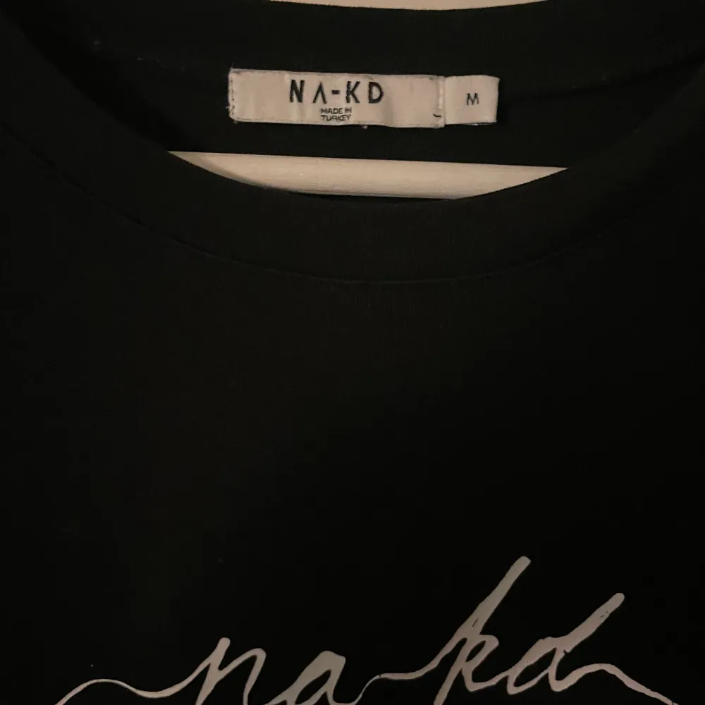 Med en vit text över bröstet där de står NA-KD. Superskön tröja och använd max två gånger. T-shirts.