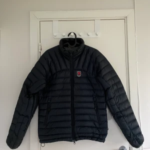 Fjällräven expedition pack down hoodie - Svart fjällräven jacka. Lite slitage vid starten av dragkedjan men annats hel. Passar perfekt för hösten/vintern. Passar 165-175
