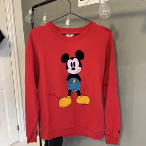 Tjocktröja - Cool röd tjocktröja med Musse Pigg på både fram och baksidan från Levis. Använd fåtal gånger och bra skick. Köparen står för frakten