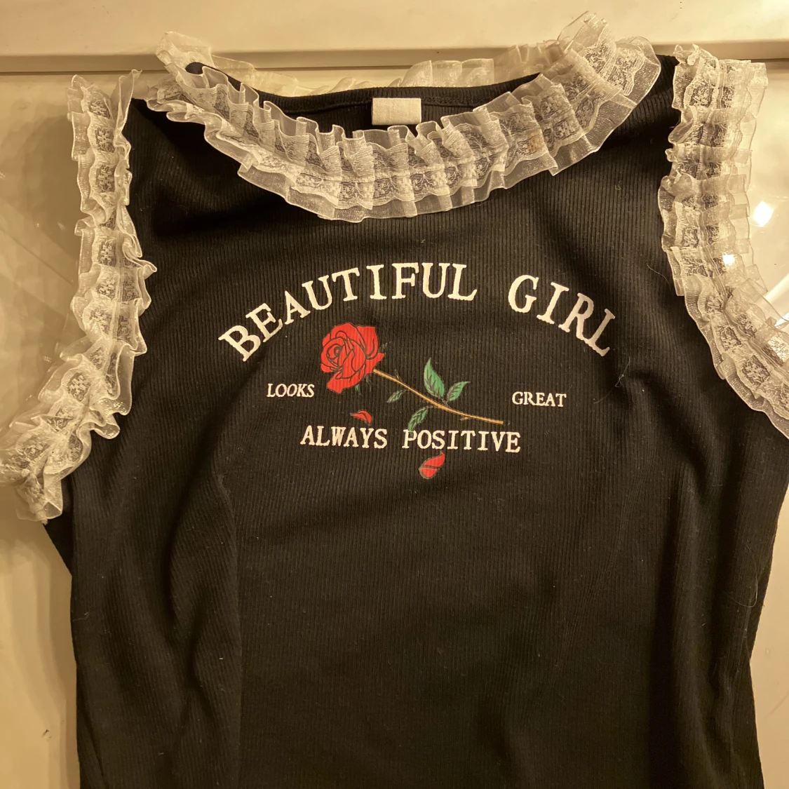 Svart topp med vitt volang, och en ros