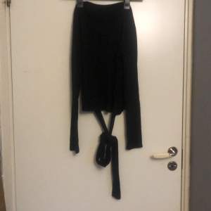 En tunn långärmad svart tröja med band som knyts i midjan från Zara.