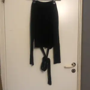 En tunn långärmad svart tröja med band som knyts i midjan från Zara.