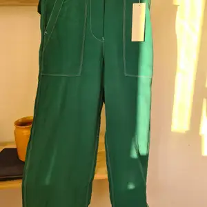 Gröna byxor med vita sömmsr, högre och tighta i midjan och lite utsvängda. Uppsydda (är ca 163 cm) går såklart att ha om man är längre. Tunt material - perfekt för sommaren! 