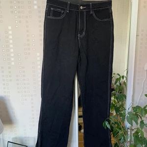 Svarta jeans med detaljer  - Svarta byxor i jeansmaterial med vita detaljer och 10 ca slits på utsidan vid foten! Nyskick! L men passar som M/L