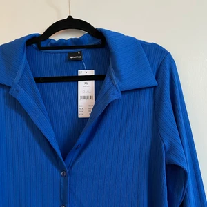 Blå skjorta - Oanvänd blå skjorta i mjukt/stretchigt material från Gina. Storlek XL men tight i modellen. Frakt tillkommer