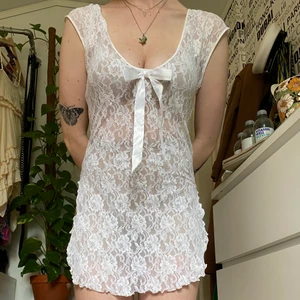 Gullig blus/klänning i vit spets med rosett  - Vit spetsklänning/blus med låg urringning, stor rosett och halvöppna sidor. Ingen etikett eller storleksmarkör men med mycket stretchigt material så passar lätt större storlekar än S/M.  Du som köper står för frakt, möts annars upp vid Stockholm City. 