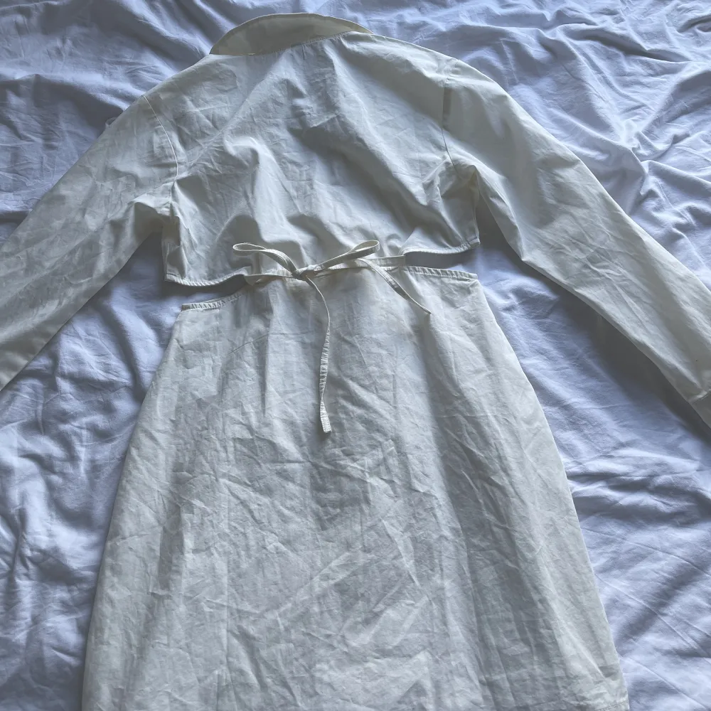 Säljer nu min vita skjortklänning då den blivit för liten. Väldigt charmig modell på den. Knappar fram och sen knyter man den i bysten för att få fram en form. Den har även vita på sidan för att framhäva lite. Passar till både fest och vardag!. Klänningar.