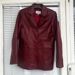 Röd läderjacka  - Jättefin röd läderjacka i fint skick säljes. Strl: 40, upplevs som en M. Några små små fläckar i ryggen (kan skicka bild) men inget som syns i helhet.   Pris: 200 kr, vid snabb affär kan priset diskuteras. 
