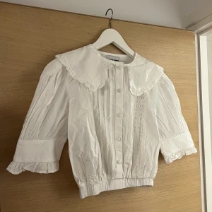 Supersöt croppad topp!  - Supersöt, croppad blus med krage och gulliga detaljer. Endast provad, så sprillans ny!  Storlek 32, men passar en XS/34 med.