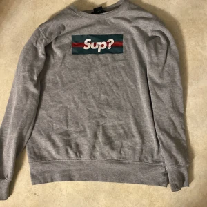 Sweatshirt  - En grå sweatshirt med trycker ”sup” på från SLIM FIT i storlek S. Köpare står för frakt!!