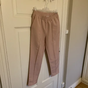 Byxor från NA-KD  - Säljer ett par snygga byxor från NA-KD. Storlek 38. Som ny! 97% polyester och 3% elastan. Med Resårband. Färgen är babyrosa. 