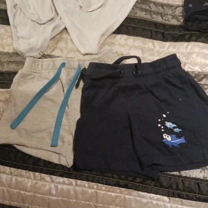 2 shorts barn - 1 st blå med fiskmotiv, 1 st hel gråa. Storlek 92-98 