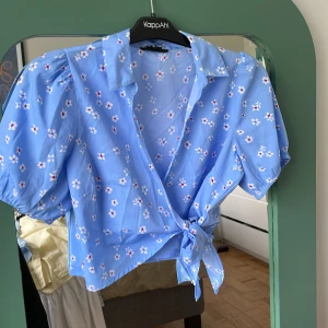 Blommig blå topp - Väldigt tunn och skön Köpt från ASOS och är använd men i väldigt bra skick Cropped så lite kortare 