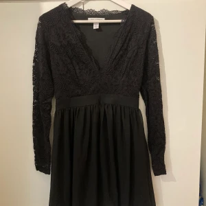 Svart spetsklänning i storlek 38 - Jättefin spetsklänning från Nelly i storlek 38 med fin urringning och spetsklädda ärmar. Fint fall nedtill och går strax nedtill knäna på mig som är 160cm.