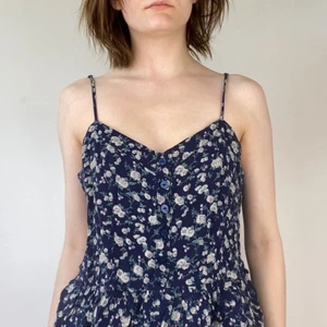 Blommigt linne - Mörkblått linne med volanger längst ner. Jättesöta detaljer såsom knapparna på framsidan. Från BikBok men köpt secondhand.