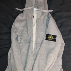 Stone Island Tröja - Säljer min Stone Island zip hoodie i strl S. Tröjan är i bra skick förutom att det finns en liten flair på tröjans vänster ärm som syns bättre på andra bilden. Därav priset.  Kan gå ner något i pris vid snabb affär!