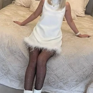 Vit Klänning  - Säljer den här vita klänning med fjädrar/ päls längst ner då den inte kommit till användning. Bara testat inte använt. 