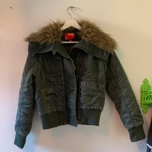 Jacka - Skit snygg grön jacka med fake päls som tyvärr inte kommer till användning. Den är i en lite kortare modell