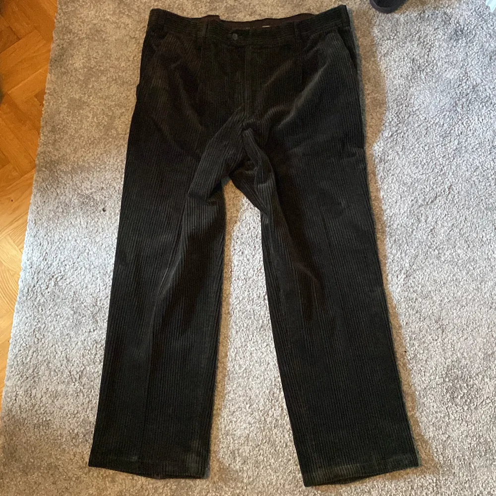 Snygga och breda manchesterbyxor i svart/brun. Ytterbenslängd: 103 cm, Midja: 95 cm, Benöppning: 24 cm. Jeans & Byxor.