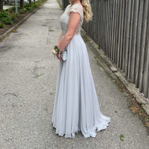 Balklänning  - Balklänning använd en gång. Färgen är silver men skiftar i blåt. Den är lite lång för mig som är 1,62cm. Nypris 4910kr, säljer för 1800kr + frakt Storlek xs 