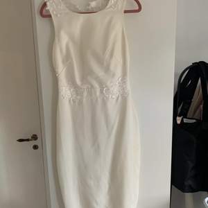 Fin vit klänning med spetsdetaljer och öppen rygg, figursydd passform. Säljes i begagnat skick. 