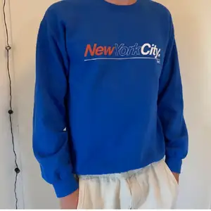 En blå sweatshirt med new york city logga på bröstet. Använd ett fåtal gånger så den är i bra skick