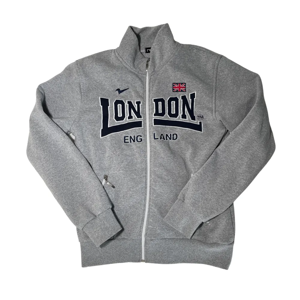 Grå zip up sweater/jacka/tjocktröja med svart tryck ”London” från märket Nas!. Jackor.