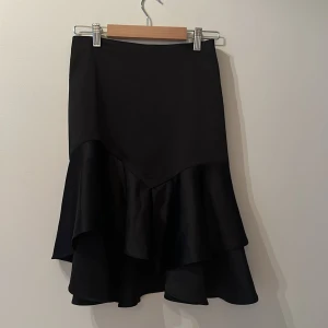 Snäv Volang kjol - Urfint skuren kjol som sitter tight vid magen men faller fint med volangerna nedtill. 